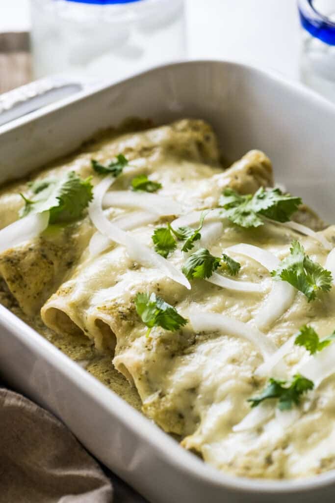 The ingredients for enchiladas suizas include corn tortillas filled with chicken, a creamy green sauce, and loads of cheese!

